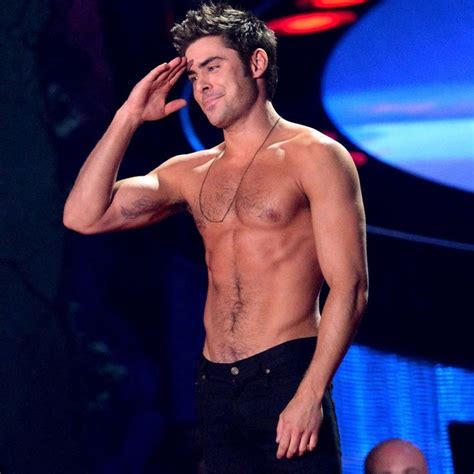 A Shirtless Man Standing On Stage With His Hand To His Face