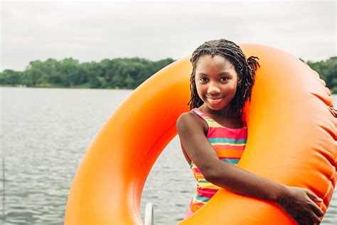 smiling black girl with orange inner tube by stocksy contributor gabi bucataru stocksy