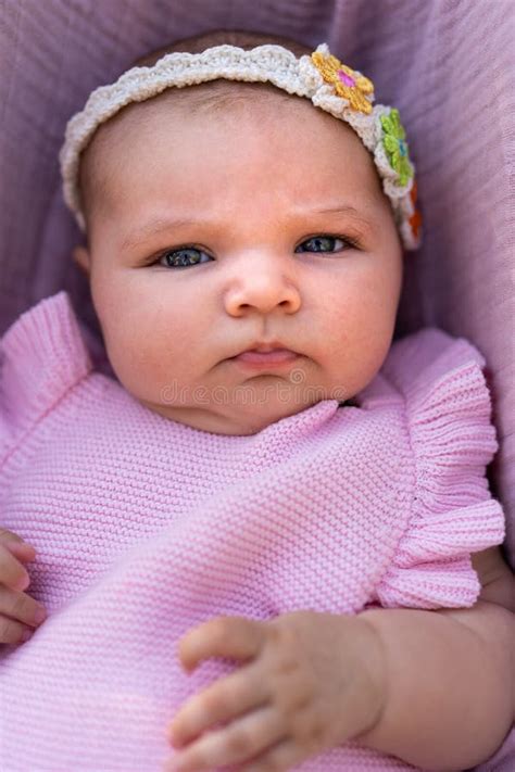 Newborn Baby Girl Wearing Pink Knitted Clothes And A Floral Head