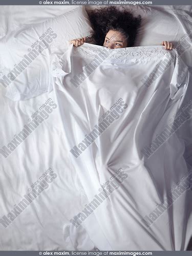 Young Woman In Bed Peeking From Under A Blanket Fashion Commercial