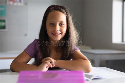 Portrait Of Smiling Caucasian Elementary Schoolgirl Sitting At Desk In Classroom Stock Image
