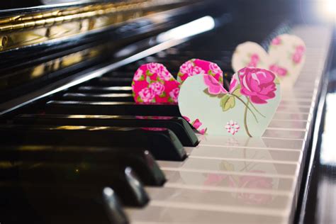 two paper hearts are sitting on top of a piano keyboard with pink flowers in the middle