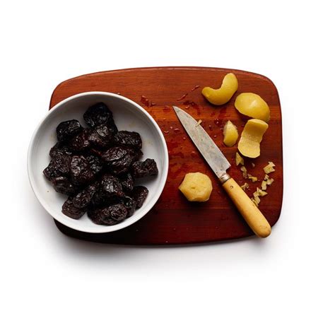 A Wooden Cutting Board Topped With Raisins Next To A Bowl Of Dried Fruit