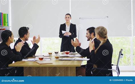 Businesswoman Stand And Presenting To Colleagues In Meeting Room Stock