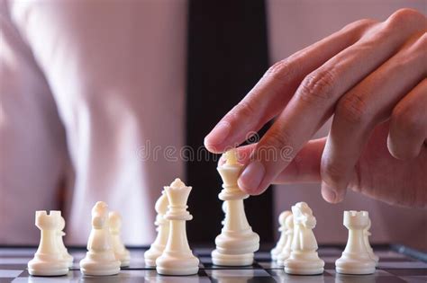 Closeup Photo Of Businessman Playing Chess And Beating Black King Stock