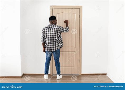Back View Of African American Man Knocking At Door Indoor Stock Photo
