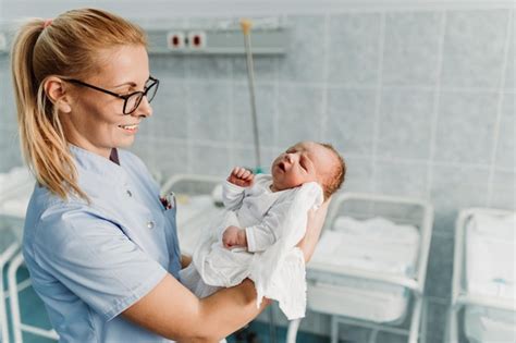 Premium Photo Young Nurse Standing In Maternity Ward And Holding