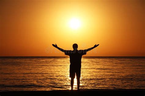 A Man On The Beach Welcomes The Sunrise Hands Are Spread Apart Stock