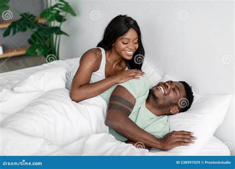 Smiling Young Pretty African American Woman Wakes Up Her Husband After