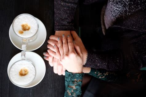 premium photo hands of lovely couple holding each other on black table with two cups of coffee