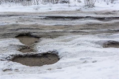 Road With Deep Holes Water Ice And Snow In Russian City In Winter