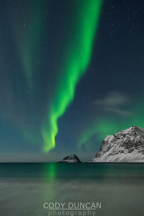 Aurora Borealis Northern Lights Shine In Sky Over Snow Covered