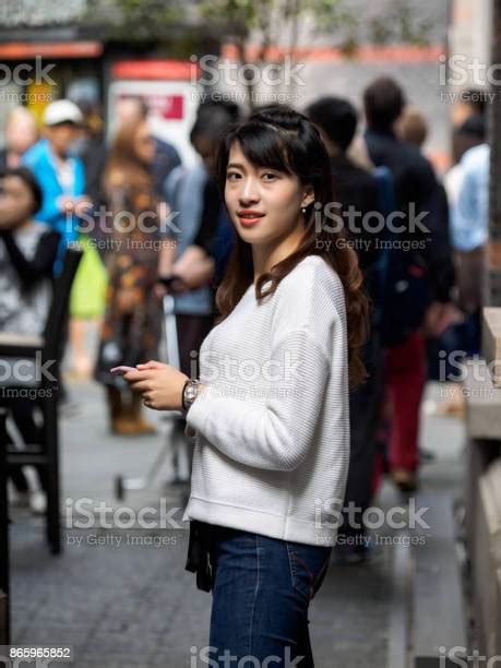 Front View Of A Happy Chinese Girl Walking And Using A Smart Phone In