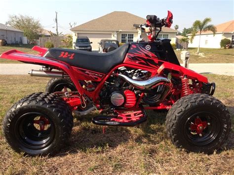 A Red And Black Four Wheeler Parked In The Grass