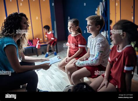The Coach Gives The Tasks To Her Little Soccer Players In A Locker Room