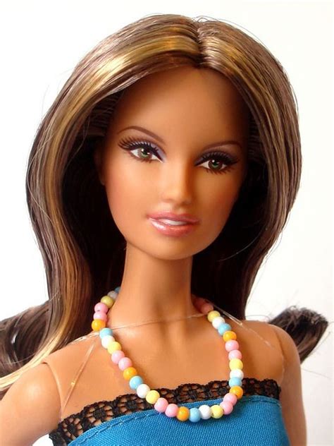 A Barbie Doll Wearing A Blue Top And Black Lace Necklace With Multicolored Beads