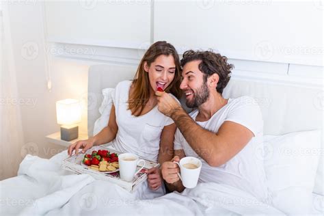 pareja enamorada desayunando en la cama joven pareja caucásica desayunando romántico en la cama