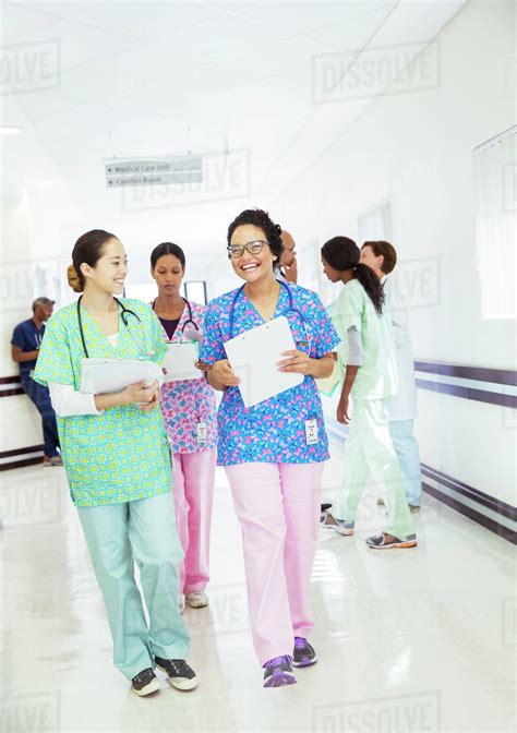 Smiling Nurses Talking And Walking In Hospital Corridor Stock Photo