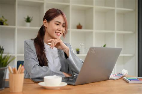 Successful Young Asian Businesswoman Working At Her Office Desk Using