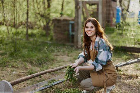A Young Woman Feeds Her Chickens On The Farm With Grass Wearing A
