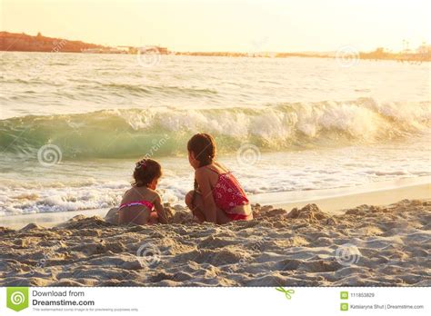 Deux Petites Filles Mignonnes Jouant Avec Le Sable Par La Mer Ondule Aux Soleils Image Stock