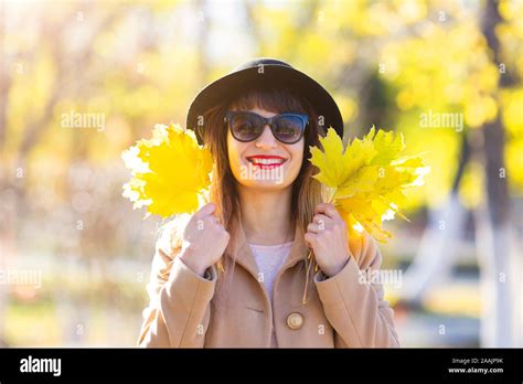 pretty woman 25 30 years old with black hair and luxurious smile with yellow autumn leaves in