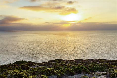 Cliff Side View Of Pacific Ocean At Sunrise With Sunrays Stock Photo