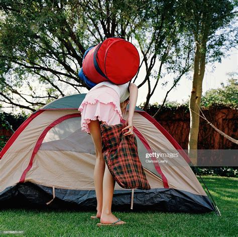 Girl Holding Bags Bending Over By Opening Of Tent Rear View Photo