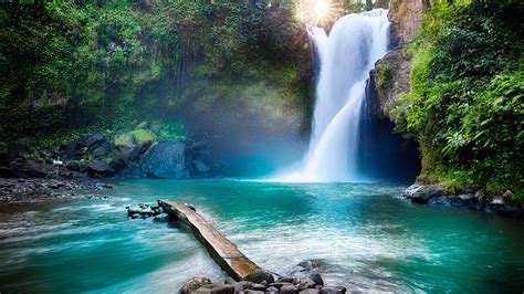 Beautiful Waterfall Between Rocks Pouring On River In Sunbeam
