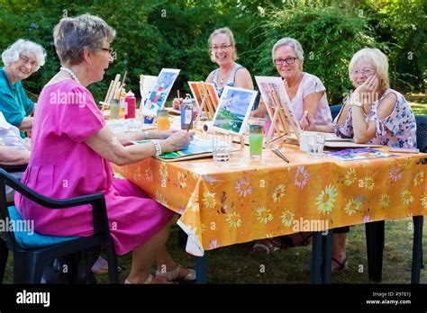 Happy Group Of Senior Ladies Enjoying Art Class Seated Around A Table