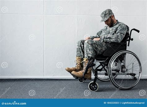 Disabled Military Man In Uniform Sitting In Wheelchair With Bowed Head