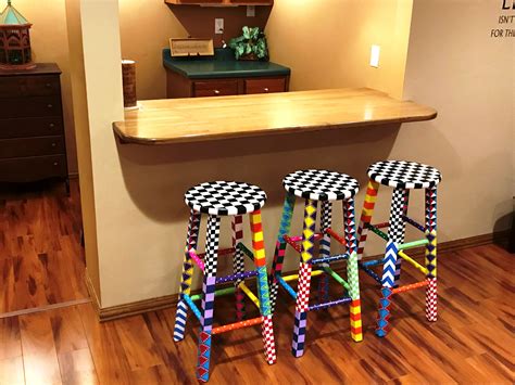 Three Colorful Stools Sitting On Top Of A Wooden Floor In Front Of A