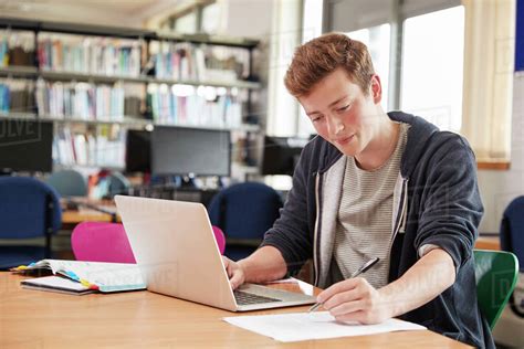 Male Student Working At Laptop In College Library Stock Photo Dissolve