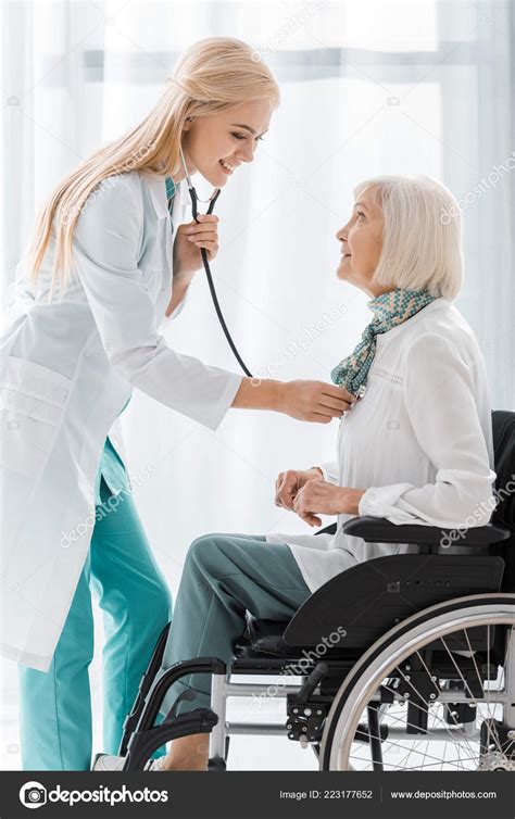 Young Female Doctor Examining Stethoscope Disabled Senior Woman Stock