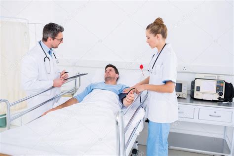 Doctors Visiting A Male Patient In Hospital Stock Photo By