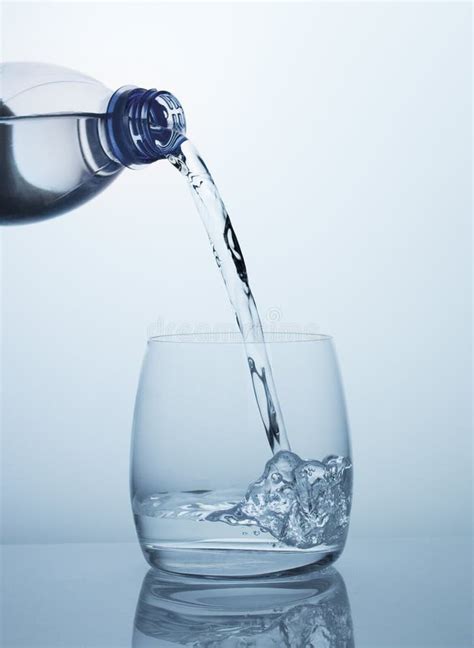 Clean Drinking Water Flows From The Bottle Into A Clear Glass With