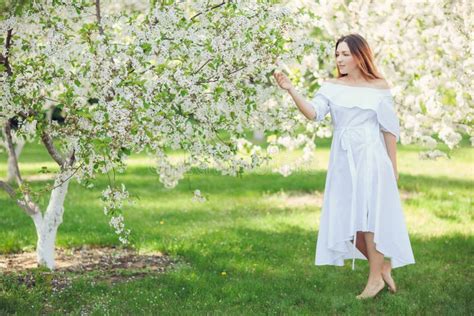 Young Beautiful Blonde Woman In Blooming Almonds Garden Stock Image