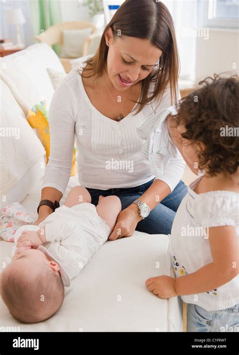 Mother Changing Babys Diaper On Sofa Stock Photo Alamy