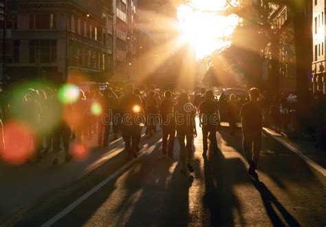 Crowd Of People Walking Down The Street Into The Bright Light Of Sunset