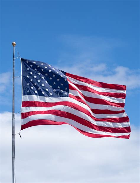 Vertical American Flag On Flag Pole With Blue Sky And Clouds Stock