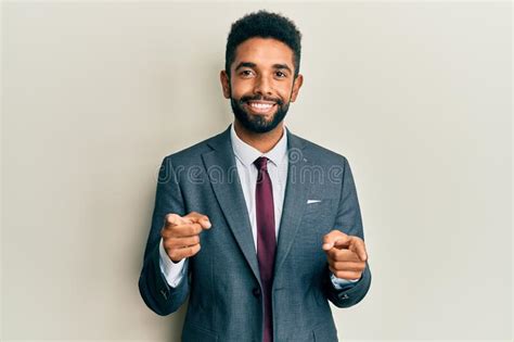 Handsome Hispanic Man With Beard Wearing Business Suit And Tie Pointing Fingers To Camera With