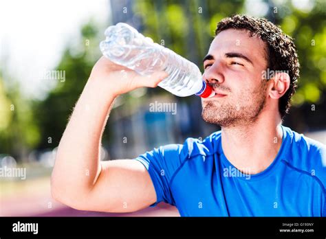Young Handsome Athletic Man Drinking Water During A Hot Summer Day To