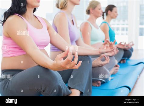 Calm Pregnant Women Meditating In Yoga Class In A Fitness Studio Stock