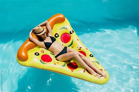 Woman On A Pizza Float In A Swimming Pool By Stocksy Contributor