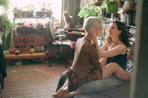 Two Girls Of Lesbians With Warm Light In A Room Sit Closely Friend To A Friend On The Sofa In