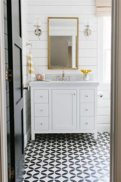 White bathroom floor tiles with small black insets can effectively ground the floor space, keeping it distinct from white walls. White Bathroom with Yellow Accents - Transitional - Bathroom