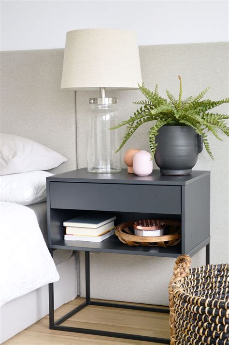A Nightstand With A Plant And Some Books On It