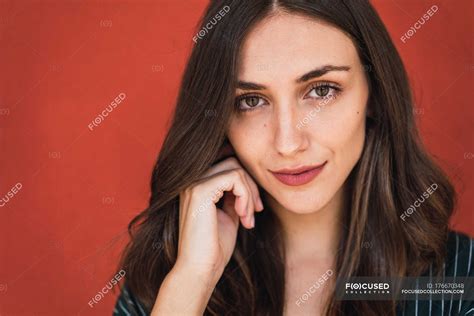 Portrait Of Pretty Brunette Woman Looking At Camera On Red Background