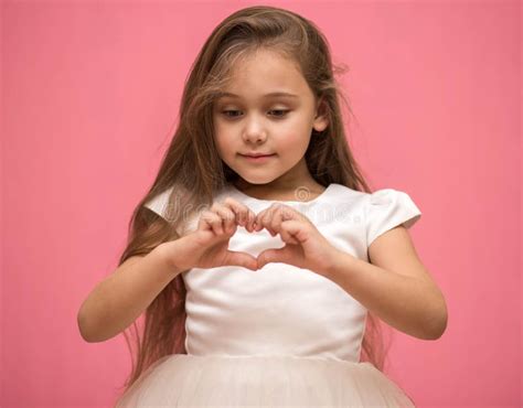 Niña Muestra Sus Dedos Con Un Corazón En Un Fondo Rosado Imagen De