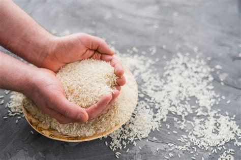 Human Hands Picking Rice From Wooden Plate Over Concrete Background